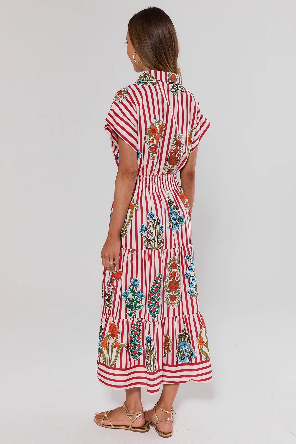 Woman standing wearing a red and white striped dress with floral patterns on a white background