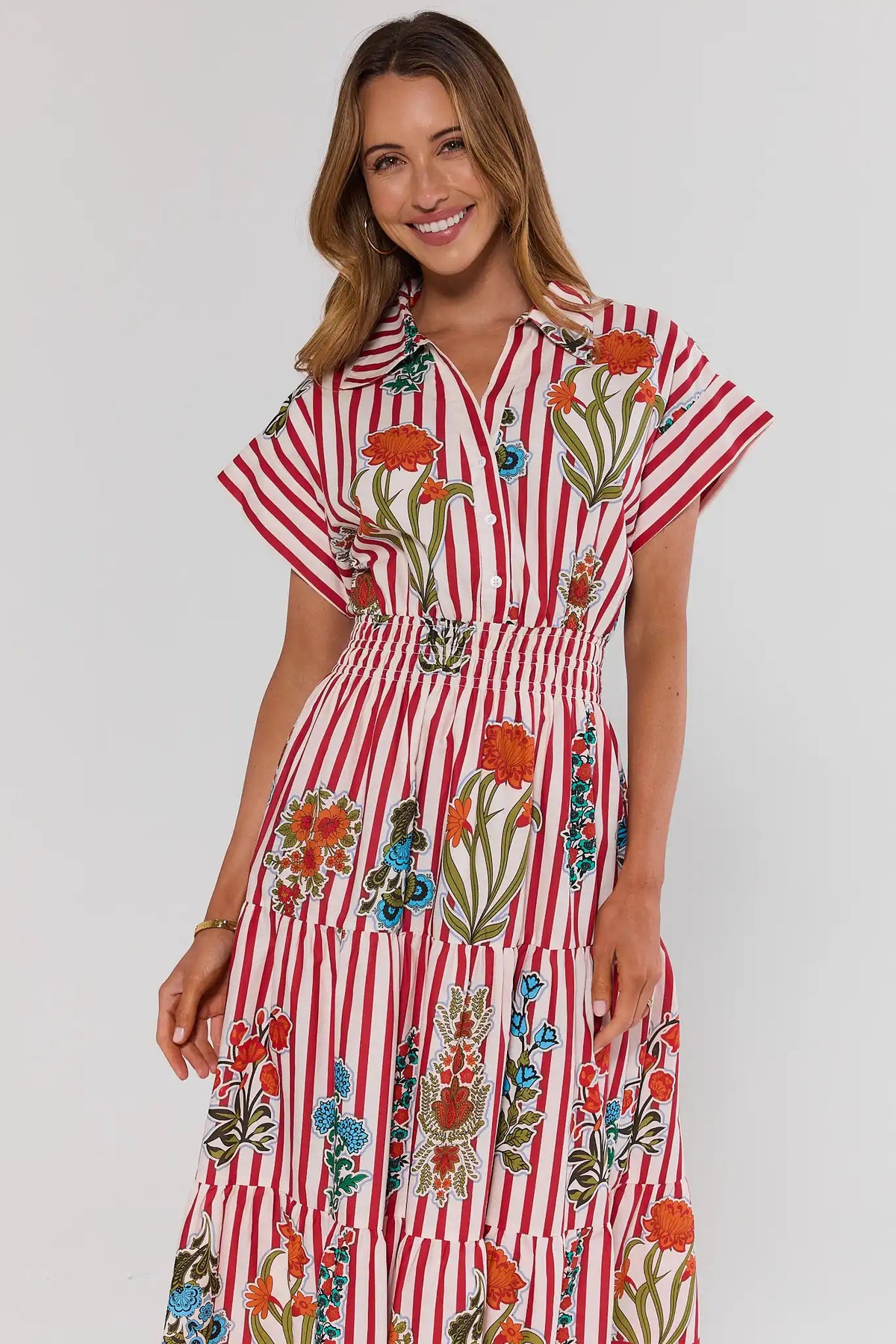Woman wearing a red and white striped dress with floral patterns on a plain background