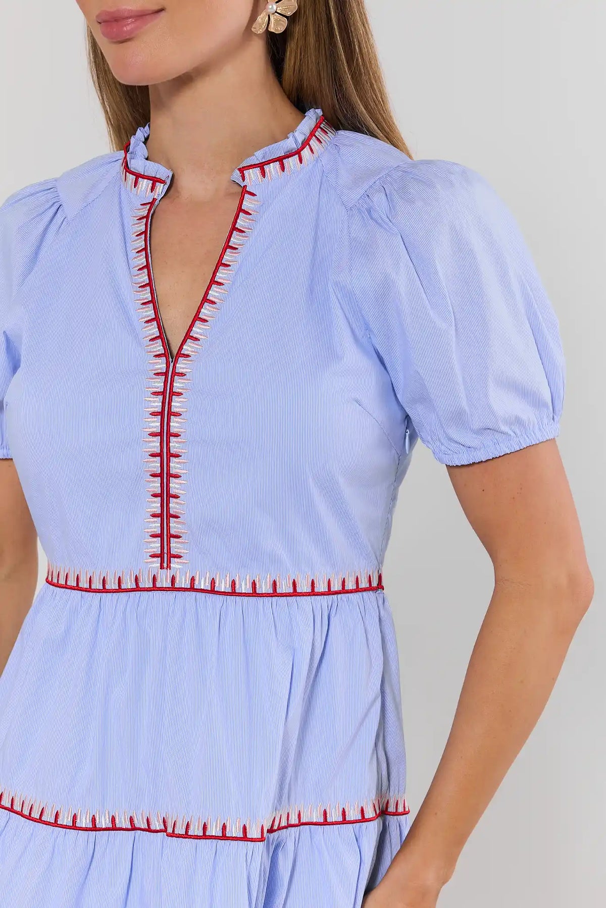 close up Light blue dress with red embroidery details on a plain background