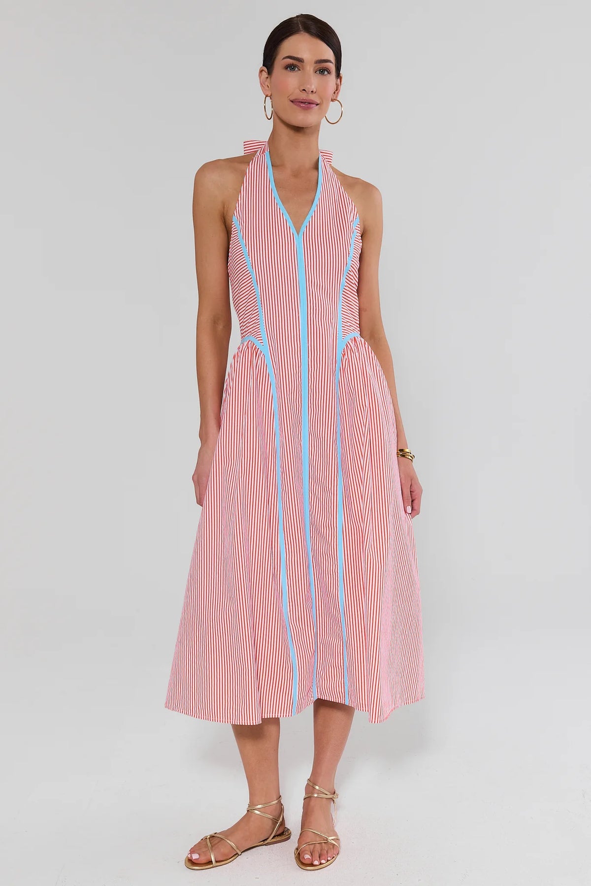Woman wearing a pink and white striped dress on a plain background standing