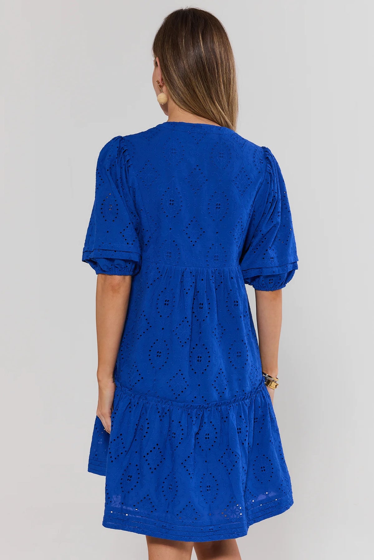 Woman wearing a blue dress with a white background standing