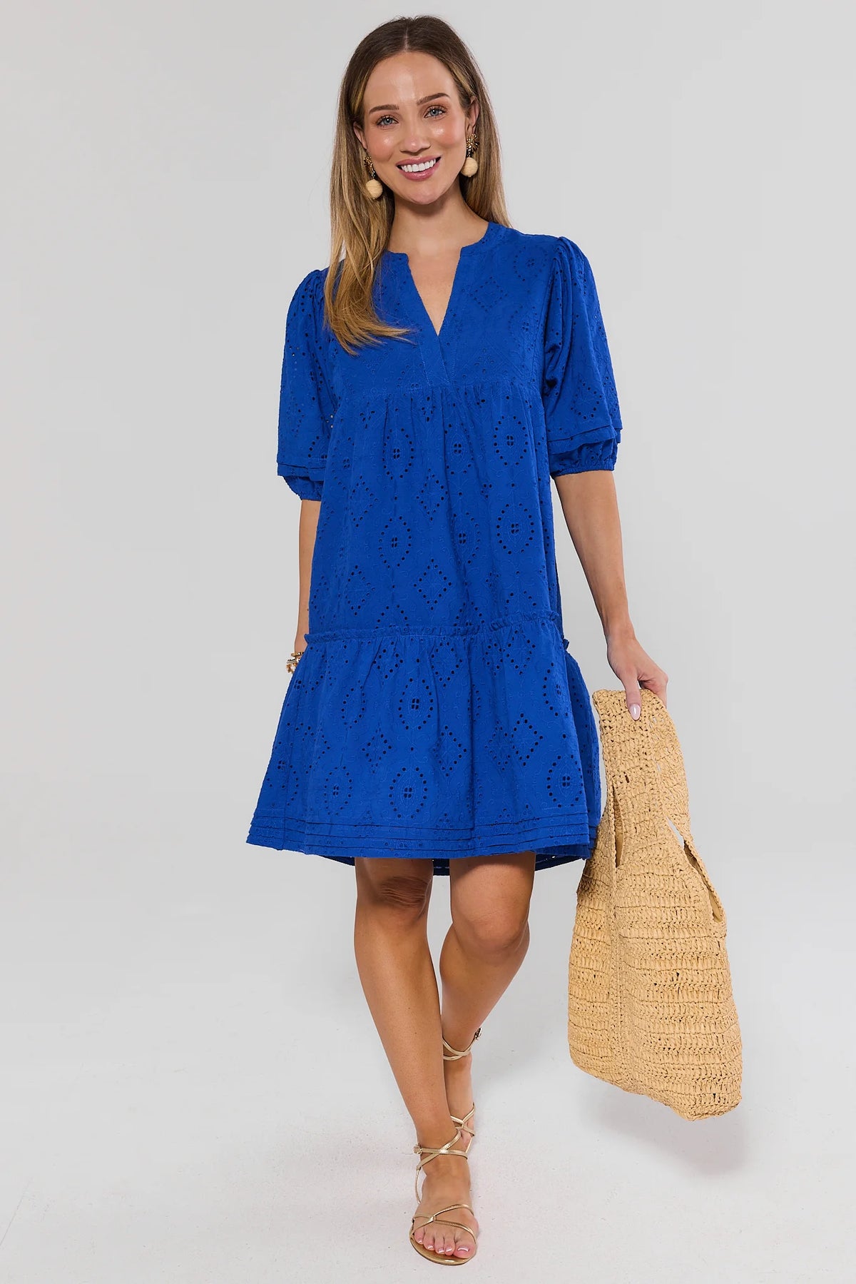 Woman wearing a blue dress holding a straw bag on a white background