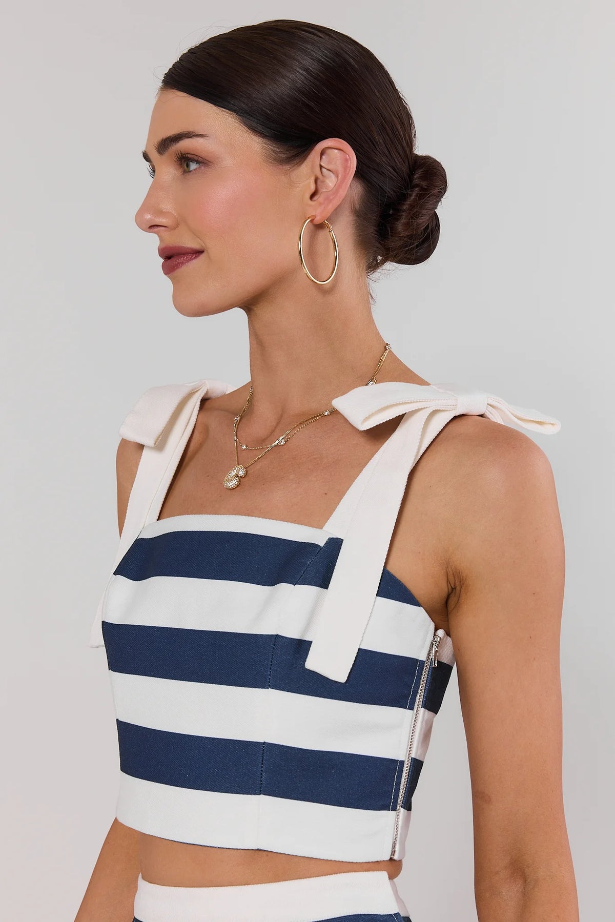 Navy striped cropped tank top with bow strap and side zipper detail, close-up side profile view | Avara