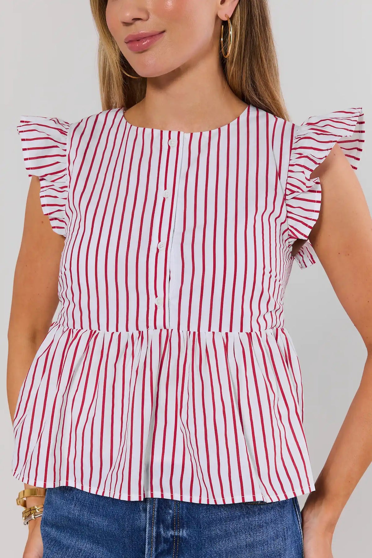 Red and white striped peplum top close-up showing flutter sleeves and button detail, front on model | Avara