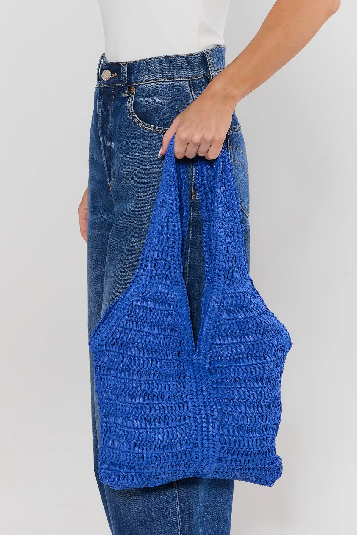 Person holding blue woven shoulder bag with jeans - On Model Side View | Avara