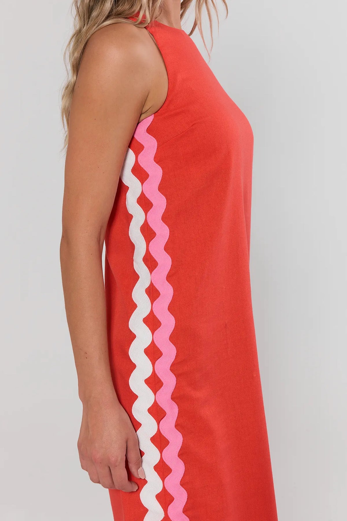 close up Red sleeveless dress with white and pink zigzag pattern on a plain background