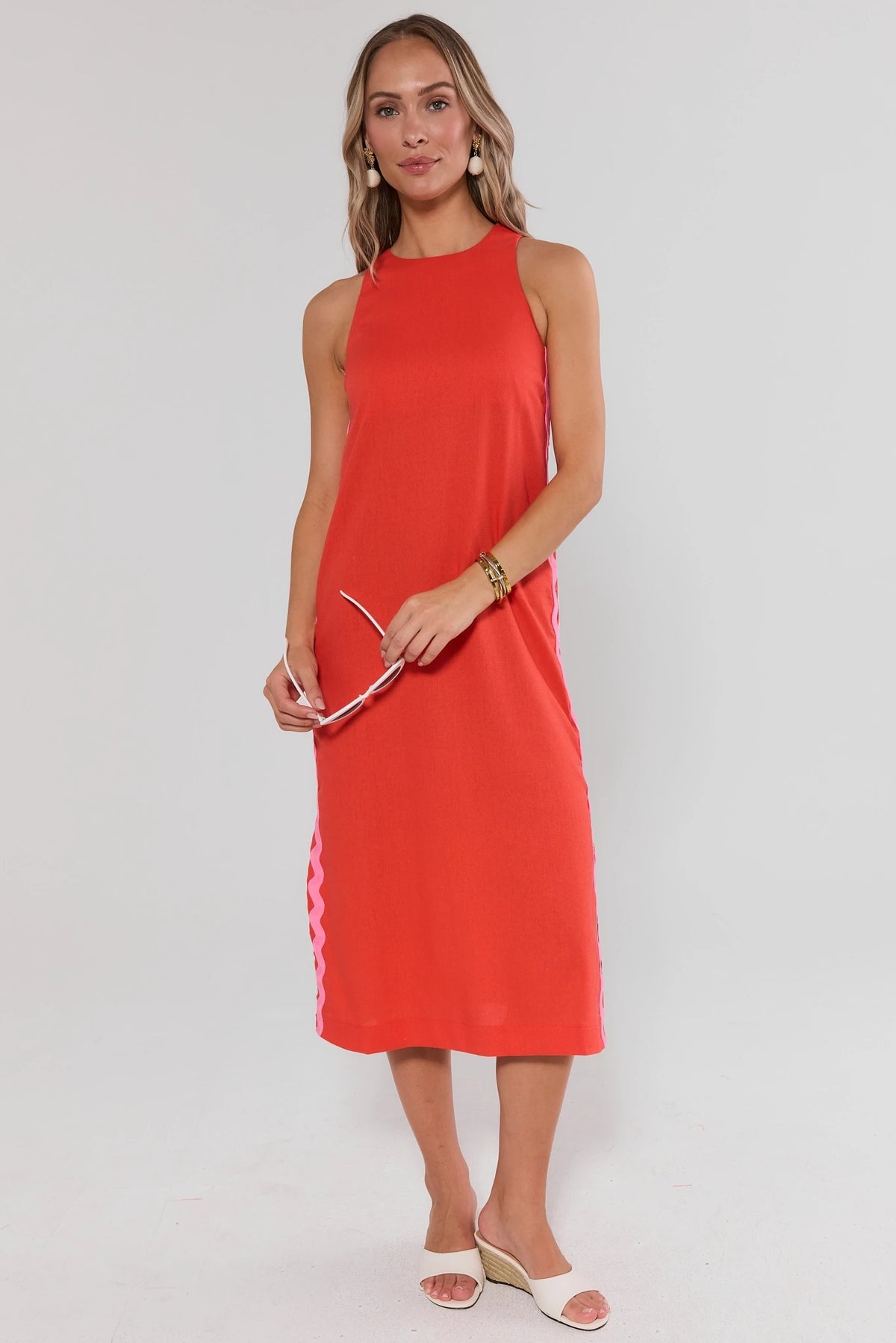 Woman wearing a red sleeveless dress on a white background standing
