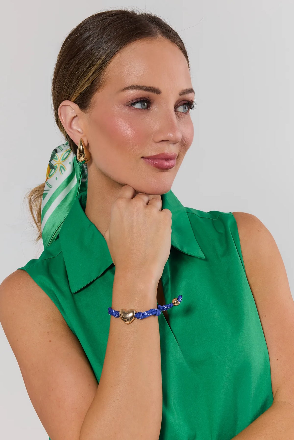 Woman wearing blue paracord heart charm bracelet with green sleeveless top and silk scarf - On Model | Avara