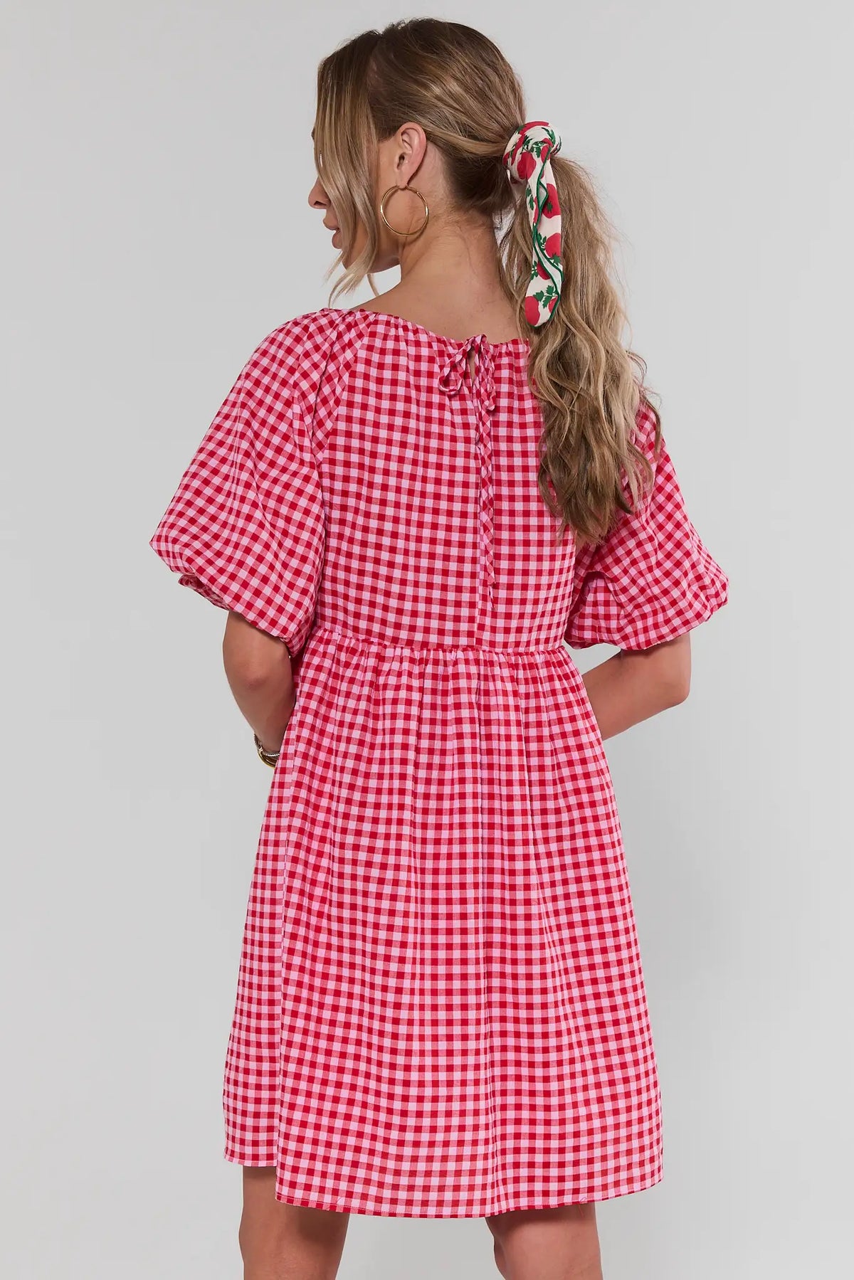 Woman standing in red gingham puff sleeve dress showing A-line silhouette, back view | Avara