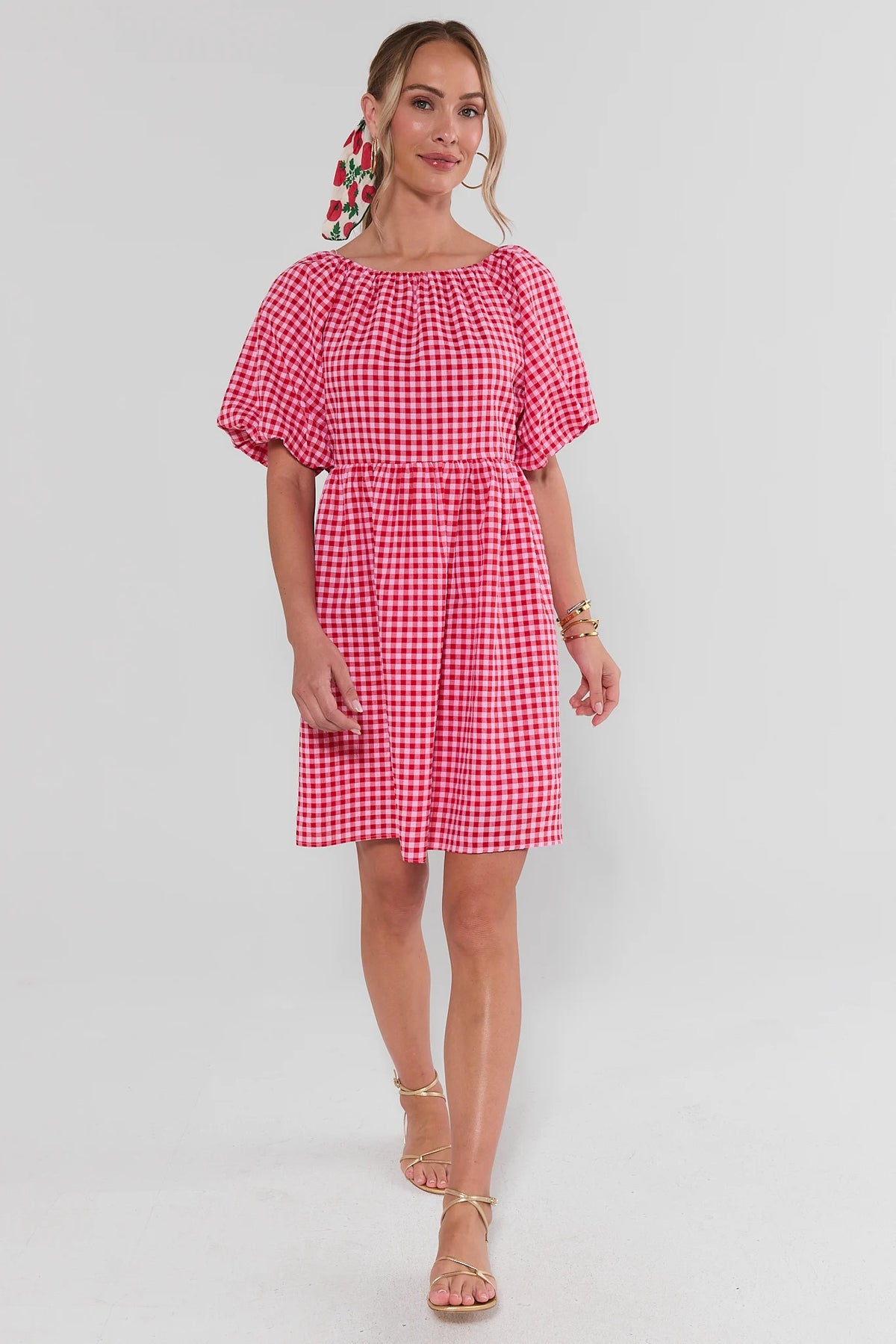 Red gingham puff sleeve short dress back view with tie closure, styled with gold sandals | Avara
