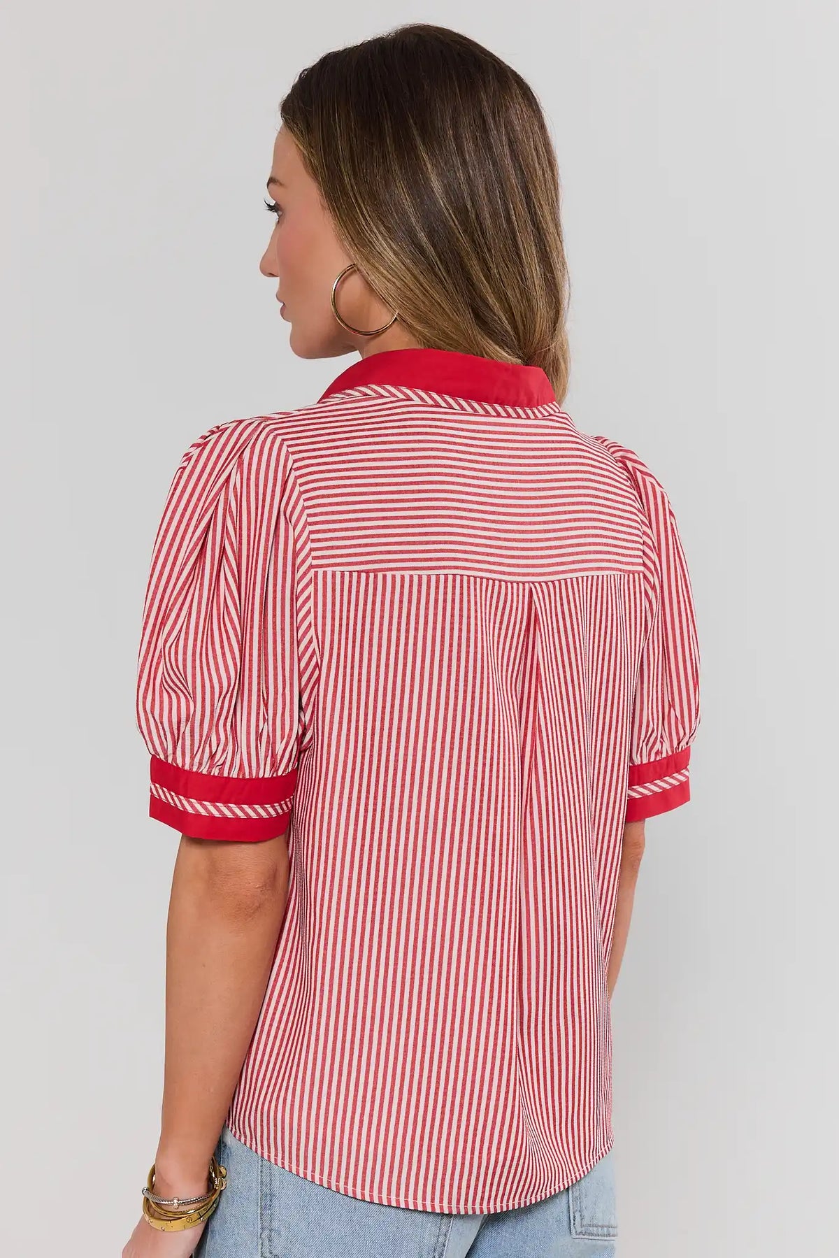 Woman wearing a red and white striped shirt against a plain background standing