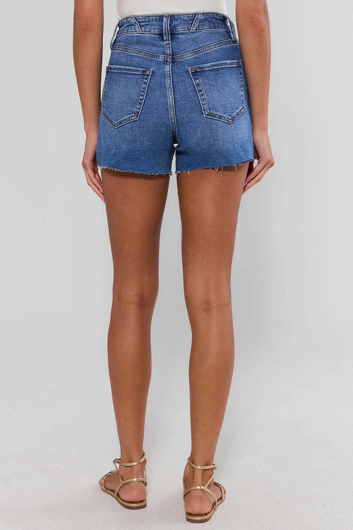 Medium wash raw hem denim shorts back view showing dual pockets and frayed hem detail | Avara