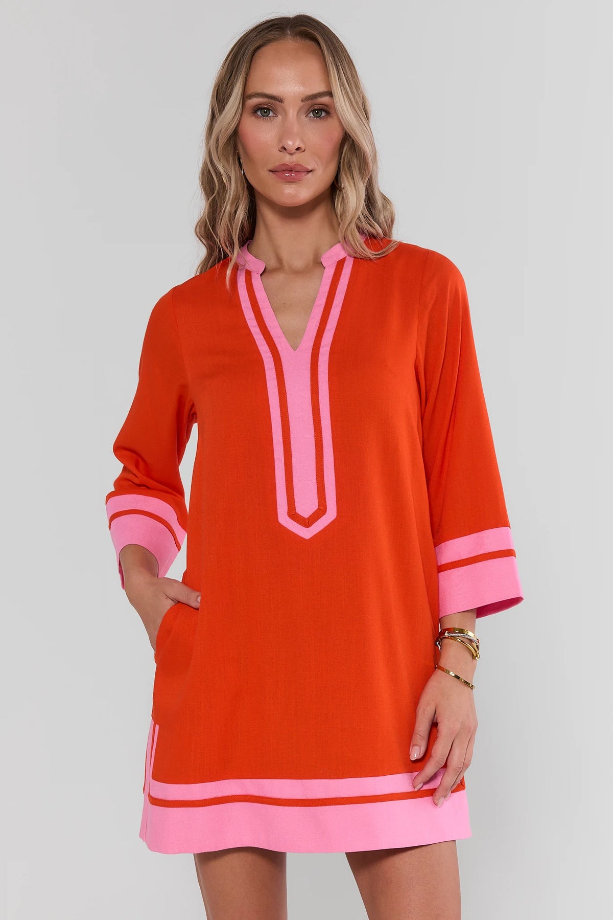 Orange and pink contrast trim tunic short dress on model, hands in pockets, front view | Avara