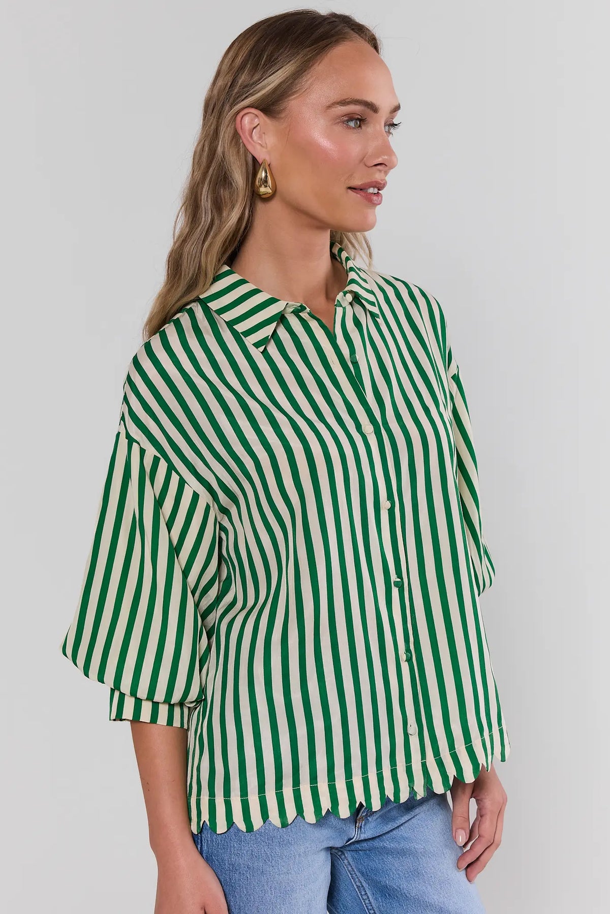 Women's green striped button-up shirt with scalloped hem over blue jeans - Side View | Avara
