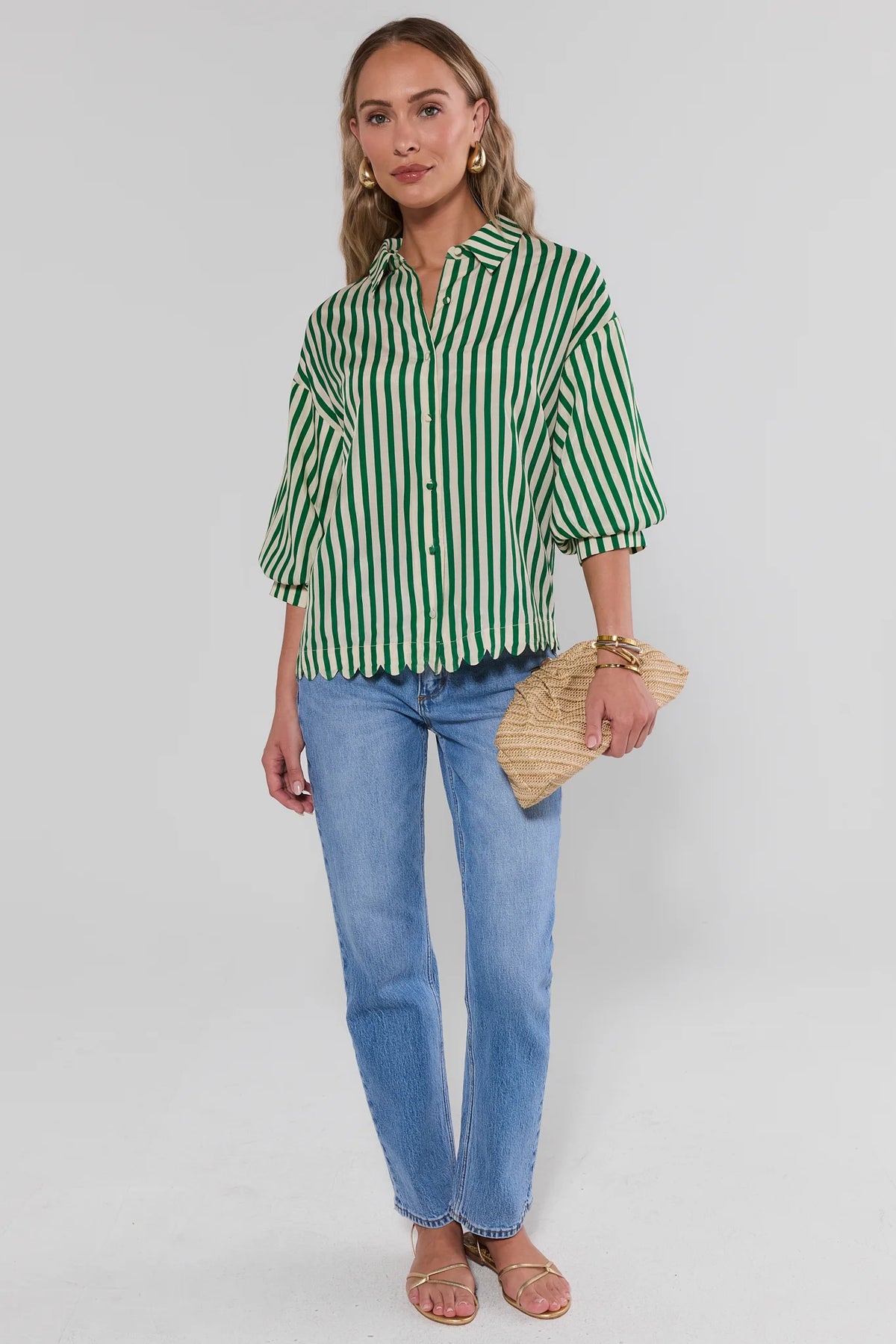 Woman in green striped top with blue jeans holding a woven clutch - Full Length Styled Look | Avara