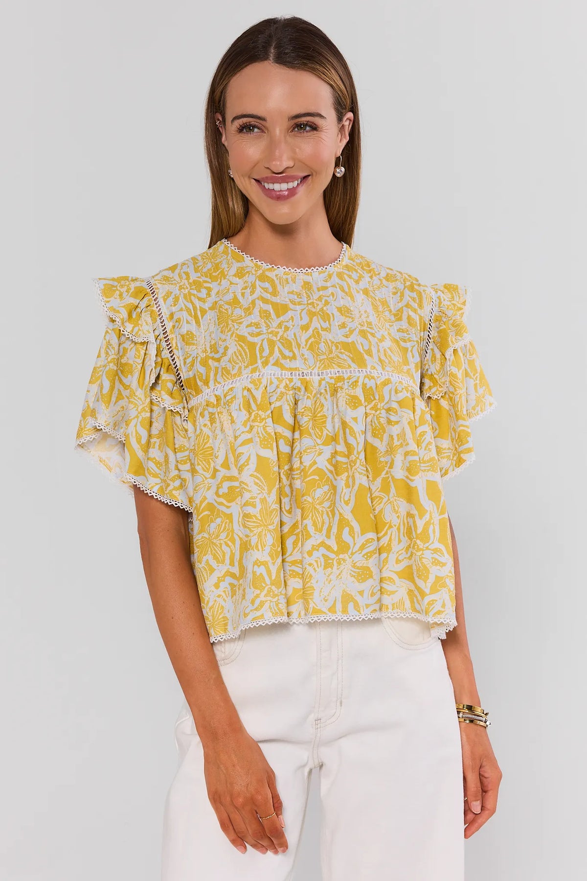 Yellow floral flutter sleeve top styled with white jeans, front view on smiling model | Avara