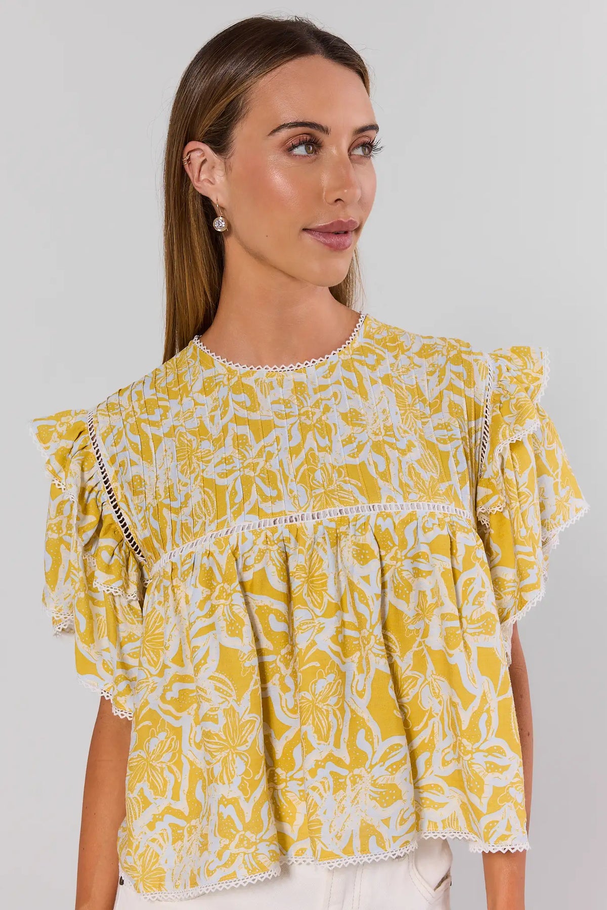 Yellow floral flutter sleeve top with lace trim, angled front view on model | Avara