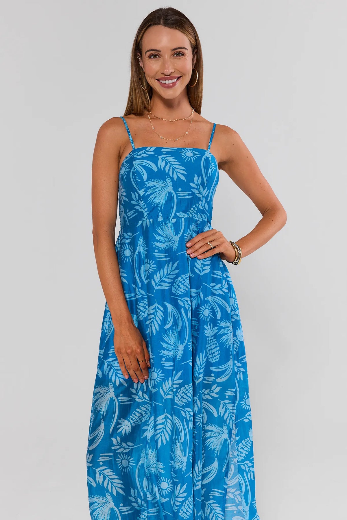 Woman in blue palm print midi dress against white background, three-quarter front view | Avara