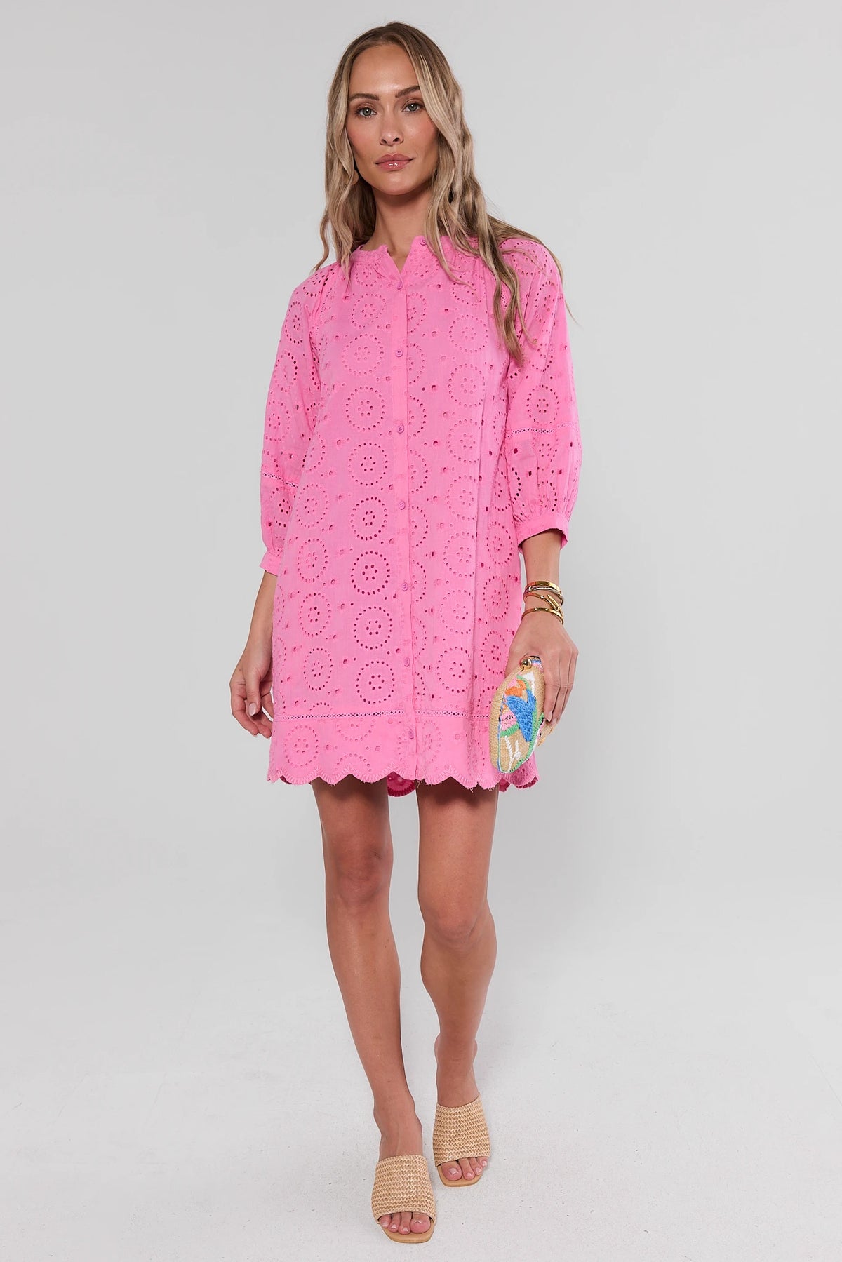 Pink eyelet mini dress full-length view styled with woven heels and beaded clutch | Avara