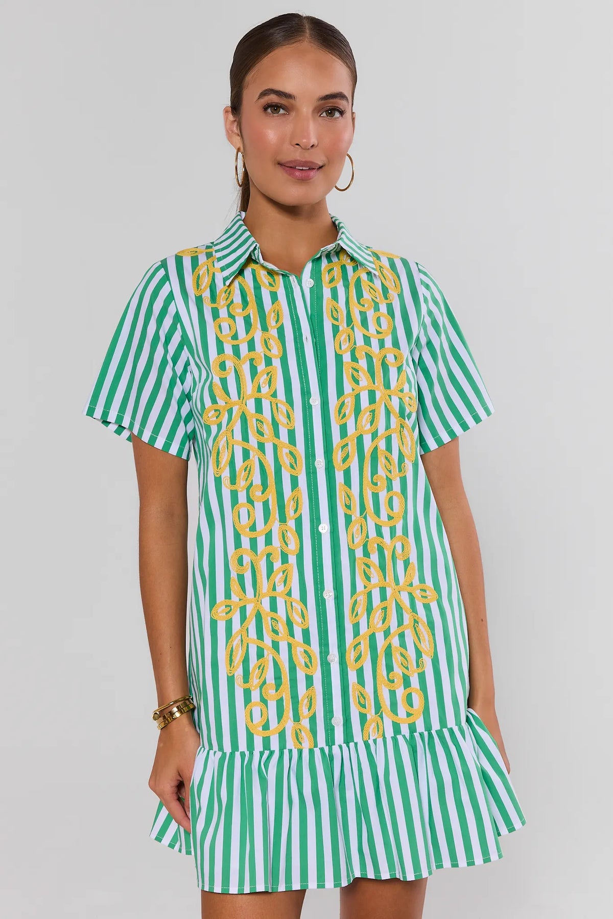 Green and white striped drop waist dress with yellow embroidery and ruffle hem, front view on model | Avara