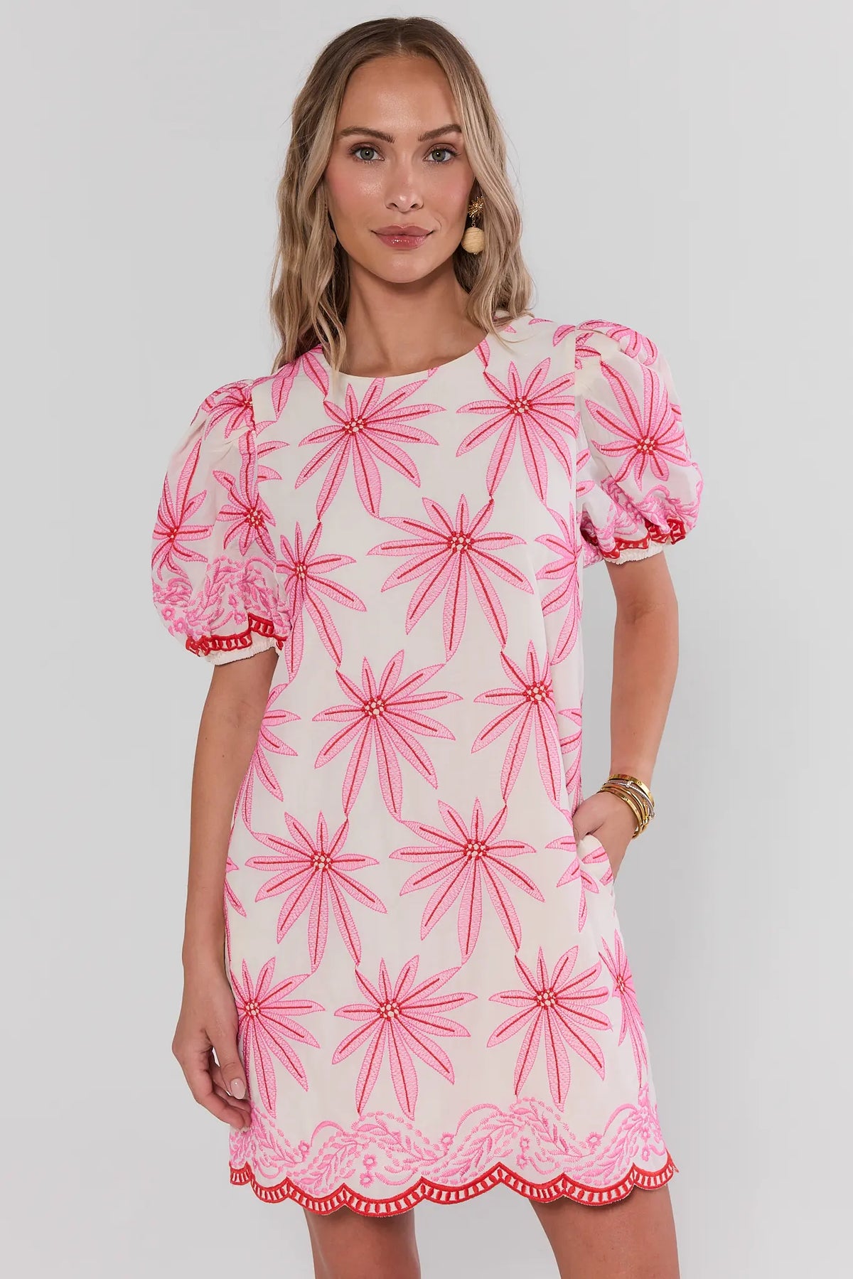 Woman wearing a pink and white dress with a floral pattern on a plain background