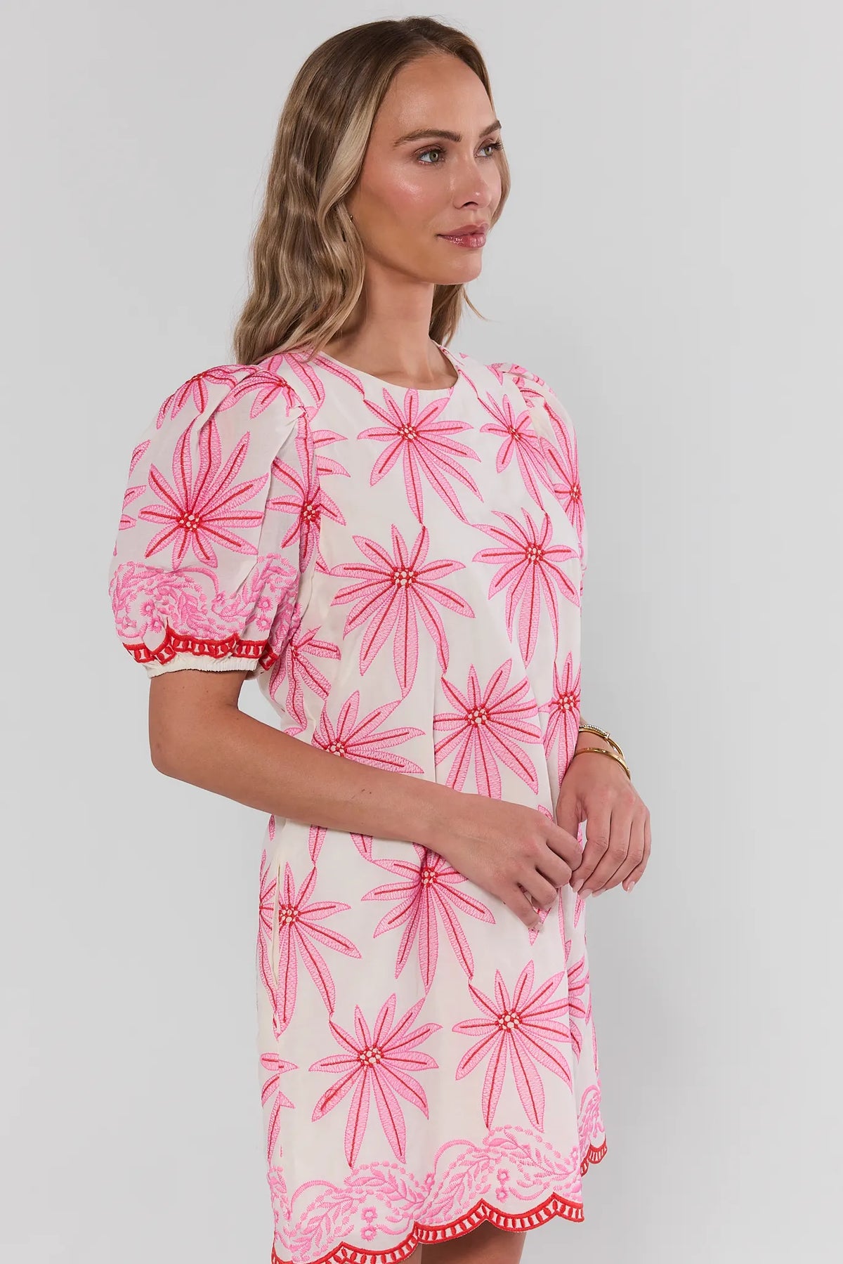 Woman wearing a pink and white floral dress against a plain background side