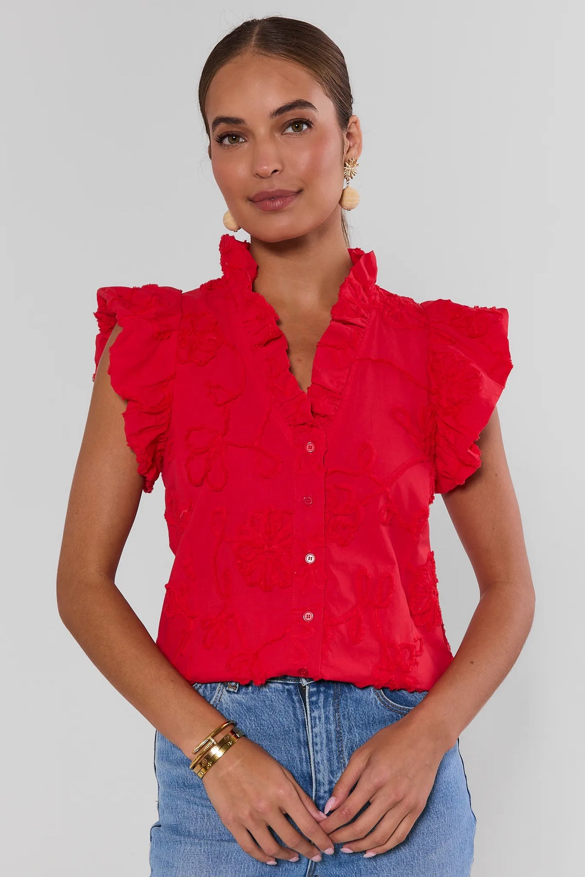 Woman wearing a red blouse with ruffled sleeves against a plain background