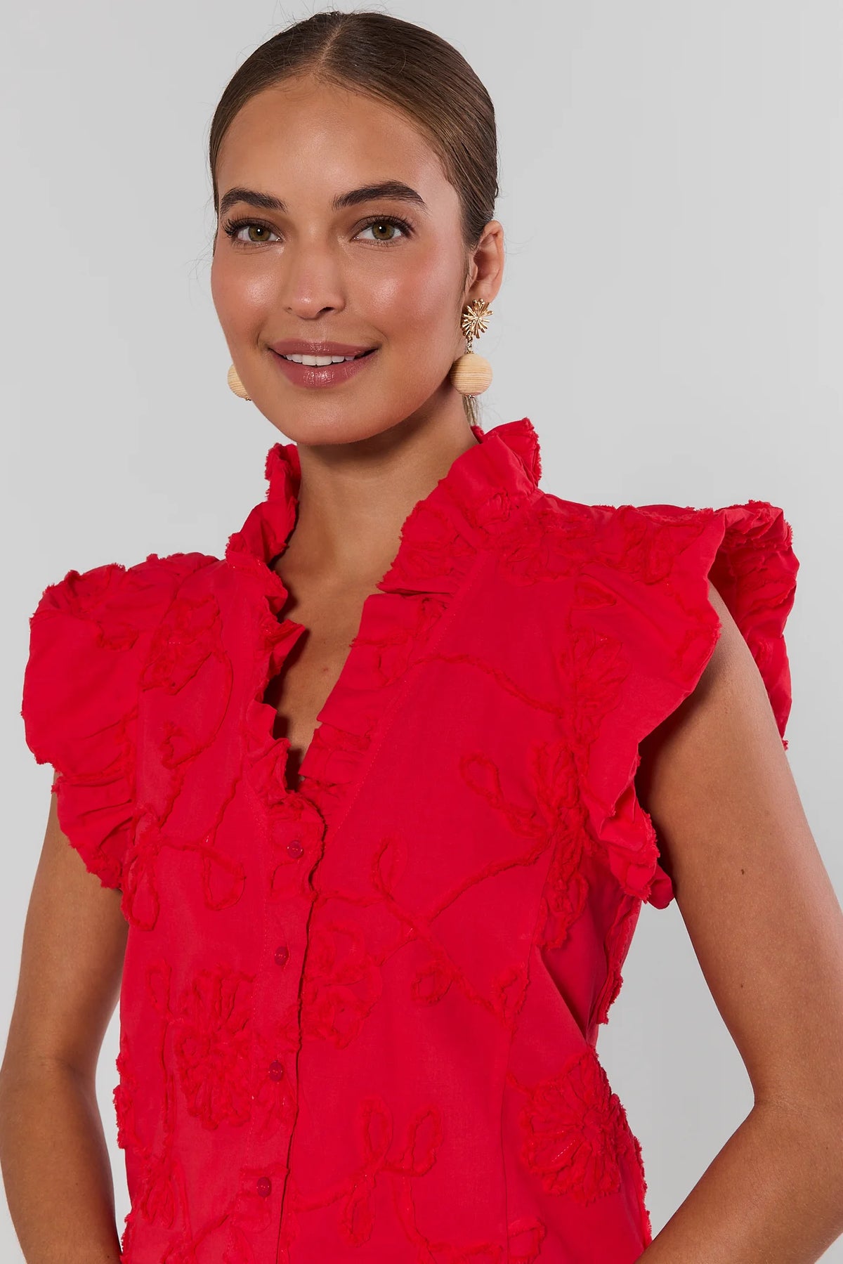 Woman wearing a red ruffled blouse against a plain background close up