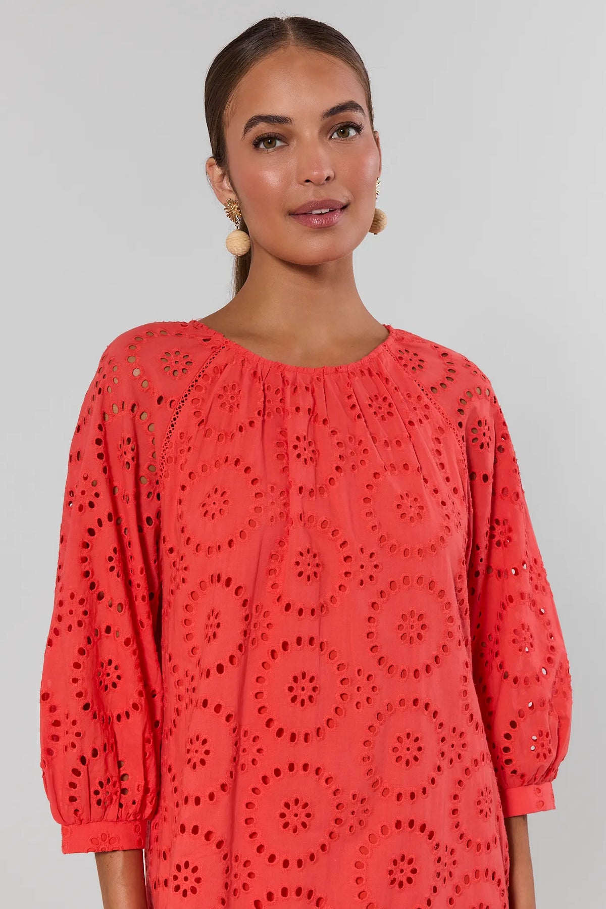 Red eyelet dress close-up showing floral cutout embroidery and gathered neckline detail | Avara