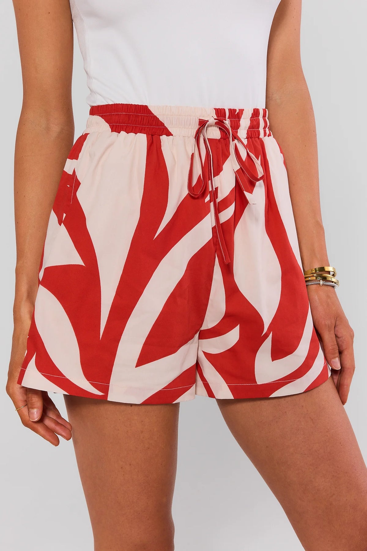 Red printed drawstring shorts with smocked waist, close-up front detail on model | Avara