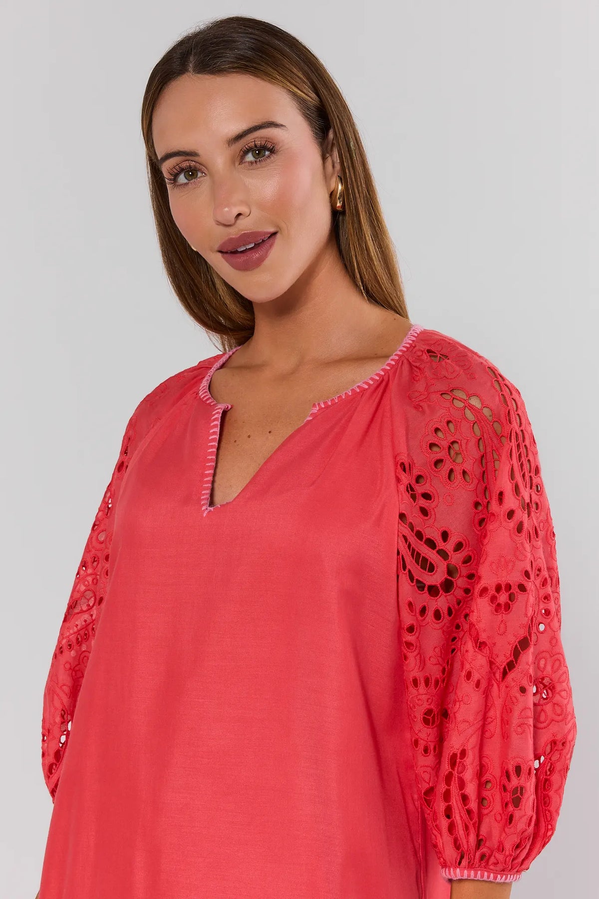 Close-up of coral eyelet midi dress V-neckline and embroidered puff sleeve detail on model, front angle | Avara
