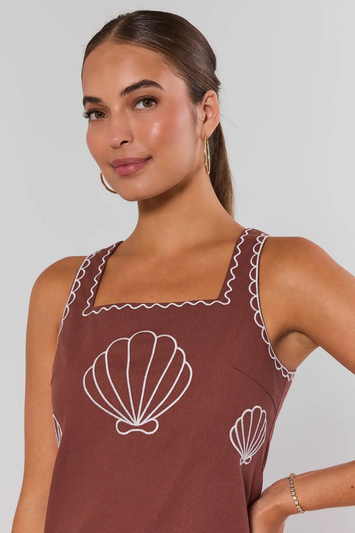 Close-up of brown embroidered dress square neckline with white shell and wave embroidery detail | Avara