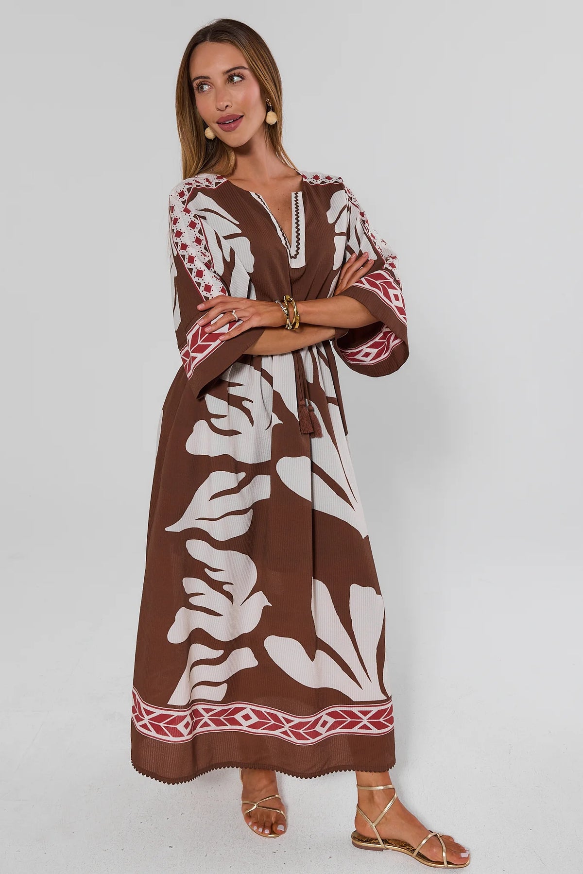 Brown Palm Print Maxi Dress with red border trim - Side View On Model Arms Crossed | Avara