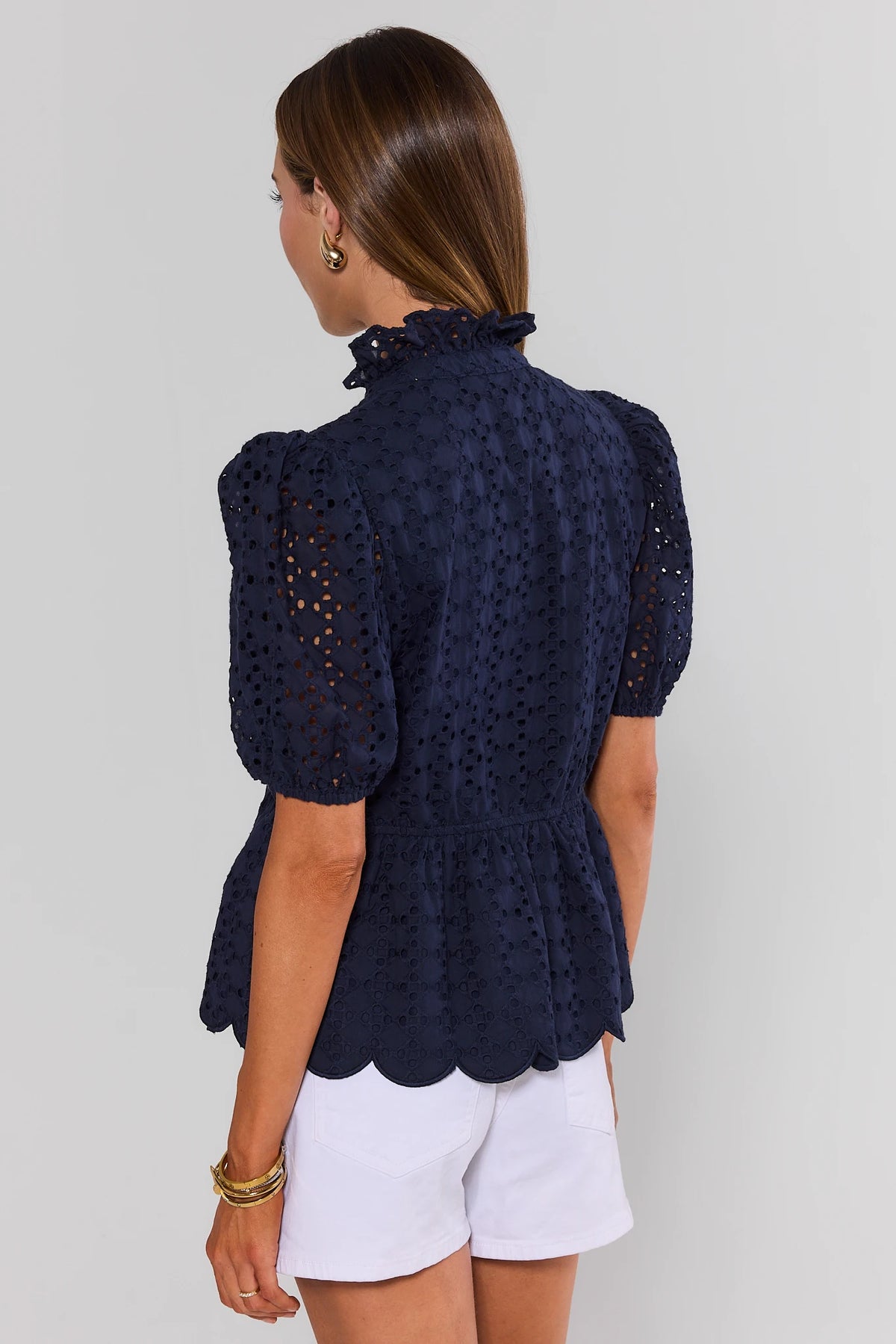 Navy blue eyelet peplum top back view showing scalloped hem, puff sleeves, and ruffle collar | Avara