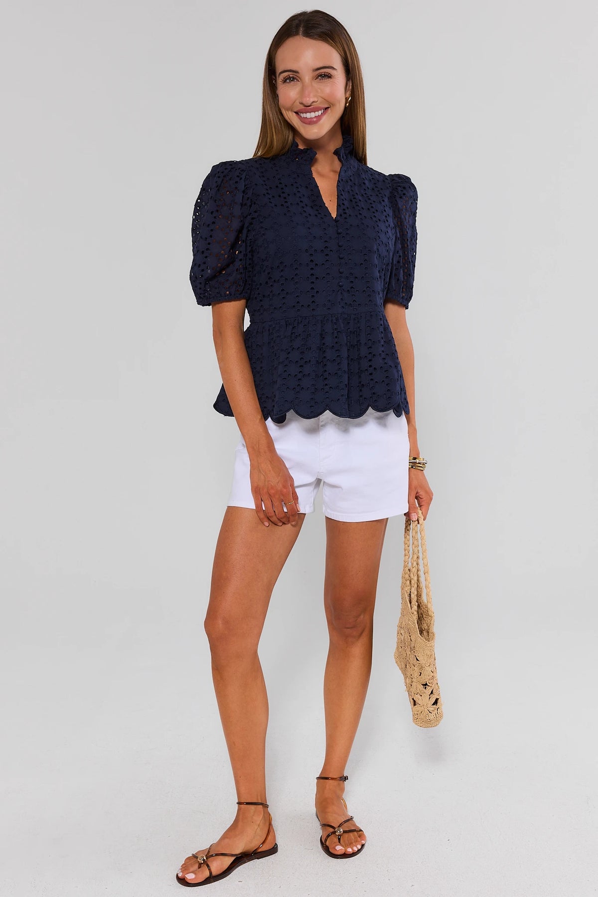 Navy eyelet peplum top styled with white shorts and crochet bag, full-length front view | Avara