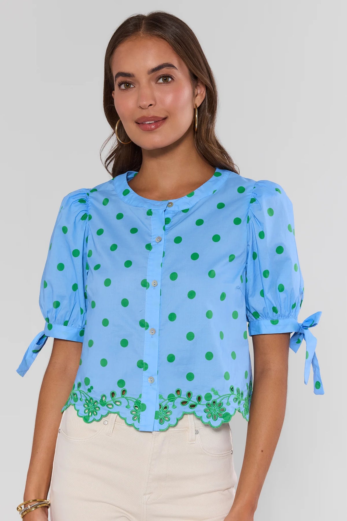 Woman wearing blue polka dot top with green eyelet trim and tie sleeves - Front View | Avara