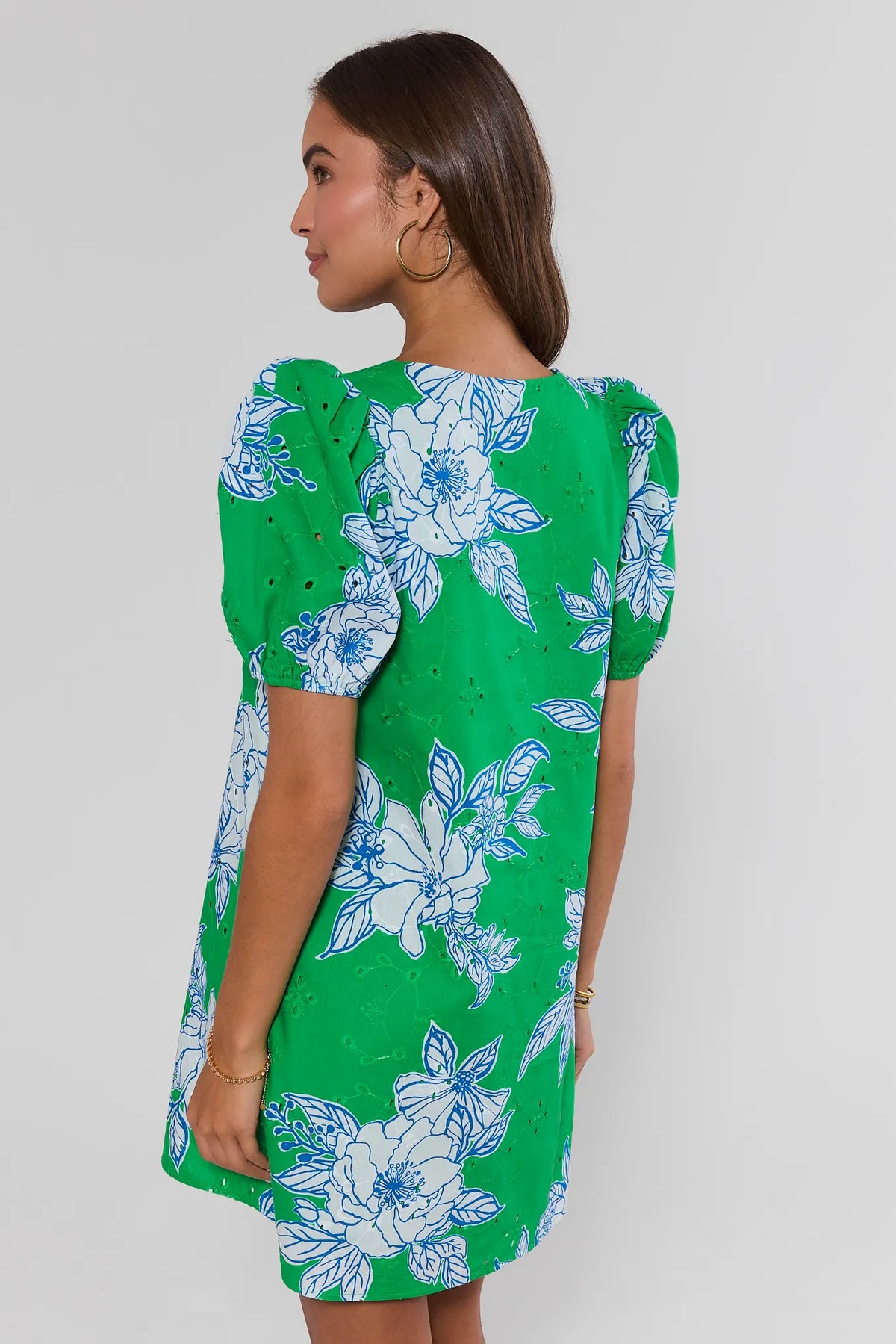Back view of green eyelet floral short dress with puff sleeves and blue floral print on model | Avara