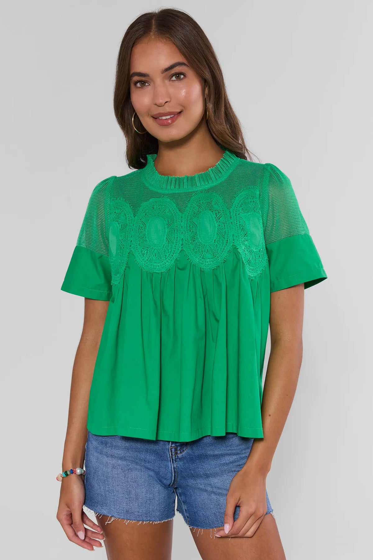 Green peplum top with embroidered mesh detail, worn with denim shorts - Front View | Avara