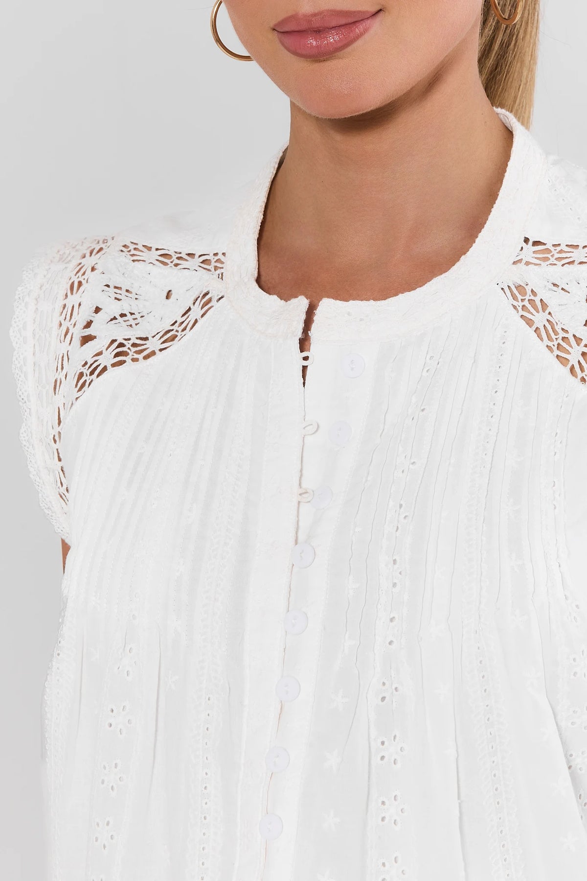 White eyelet embroidered top close-up showing lace shoulder detail and button front | Avara