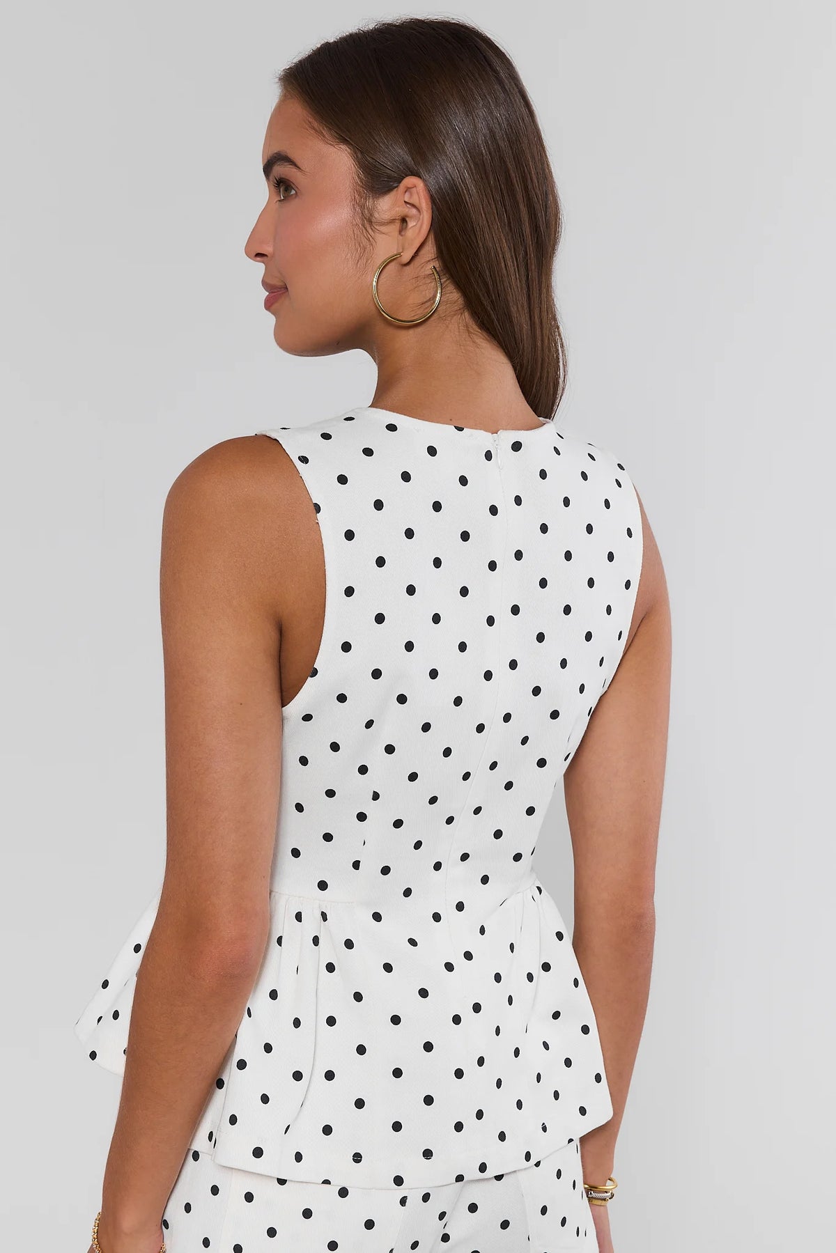 White polka dot peplum tank top back view showing zip closure and peplum silhouette | Avara