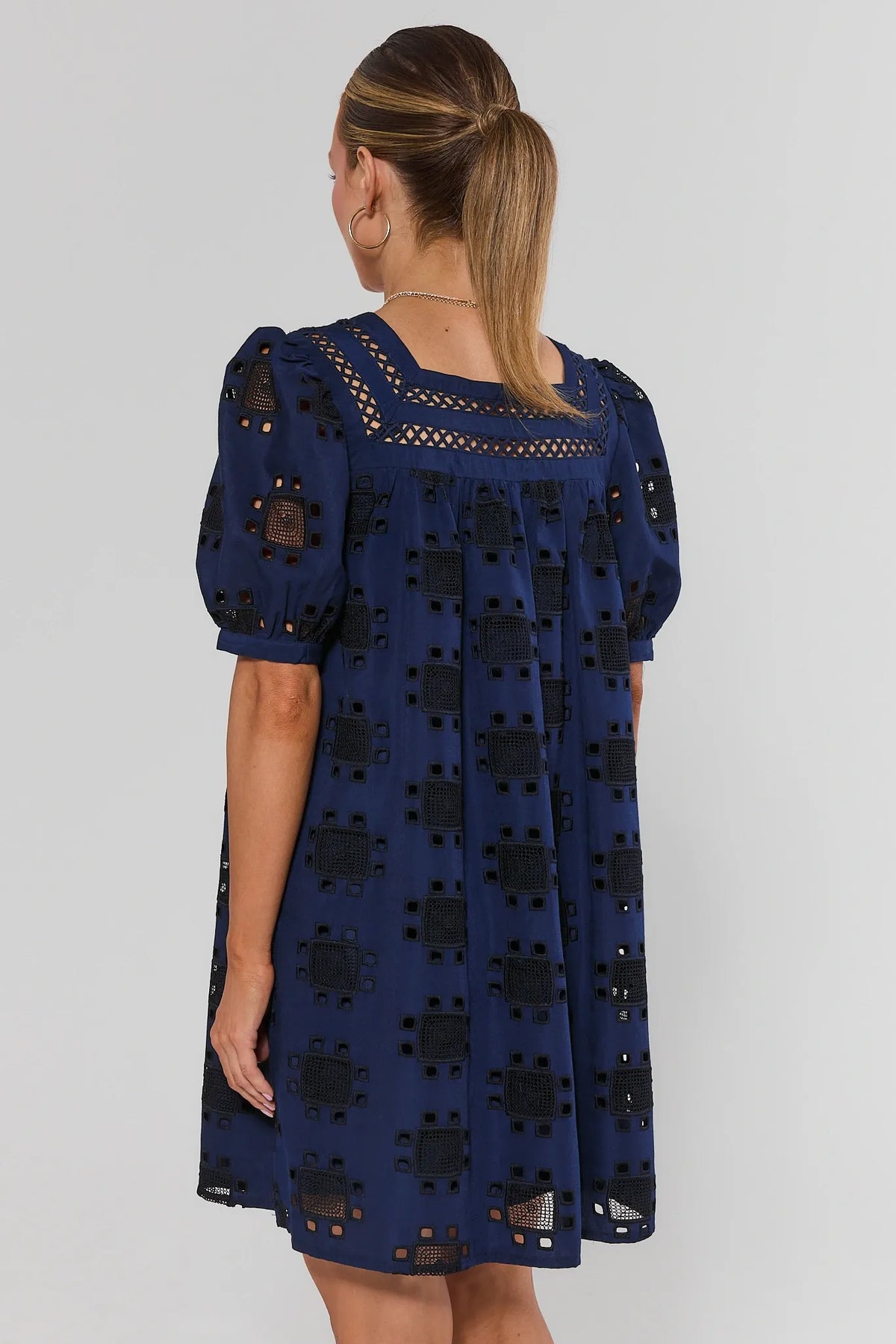 Navy eyelet short dress back view showing geometric cut-out pattern and square neckline | Avara
