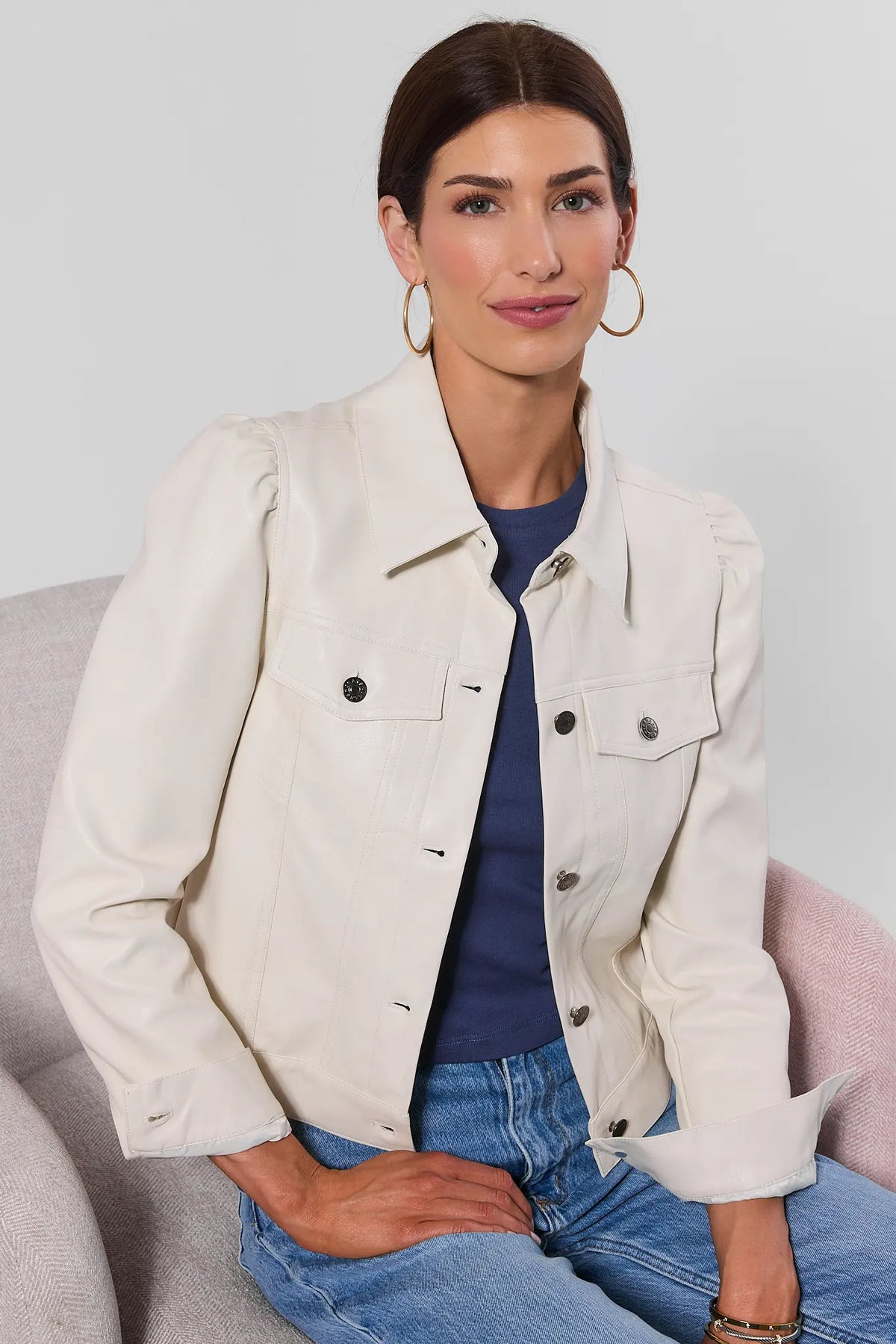 Roxanna Cream Faux Leather Jacket - On Model Seated Front View, styled with blue top and jeans | Avara