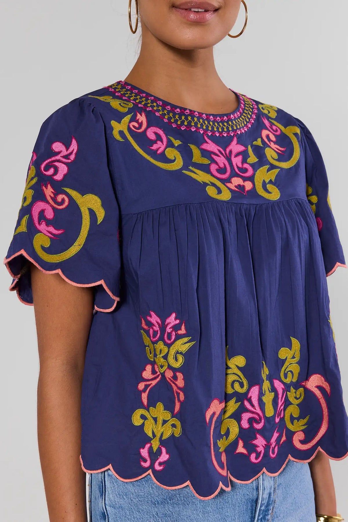 Close-up of navy THML scalloped top with pink and gold embroidery detail at neckline and sleeve | Avara