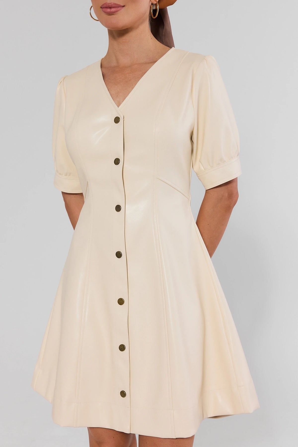 Ivory Faux Leather Short Dress close-up showing gold snap buttons, V-neckline, and puff sleeve detail | Avara