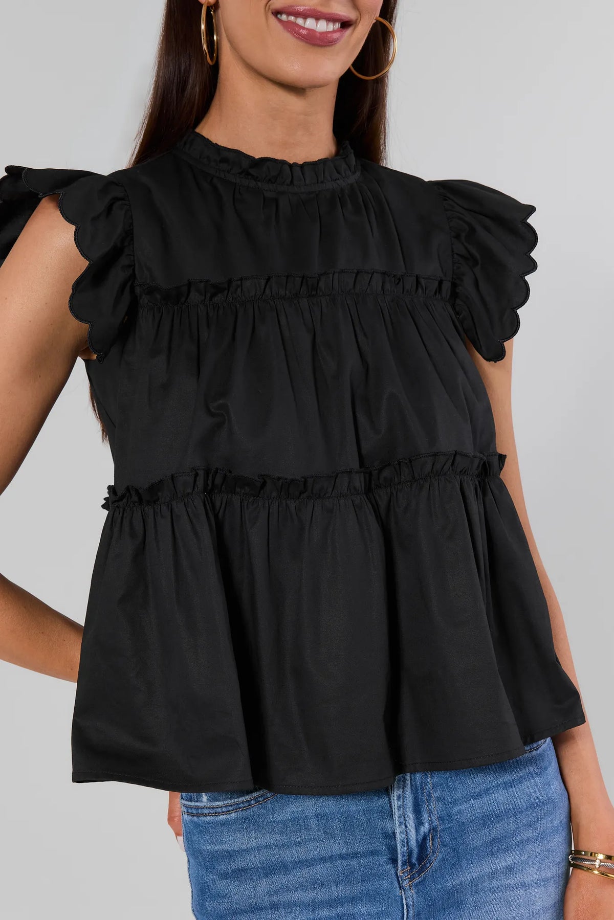 Close-up of Black Tiered Flutter Sleeve Top showing ruffle tiers and scallop detail - Front Detail | Avara