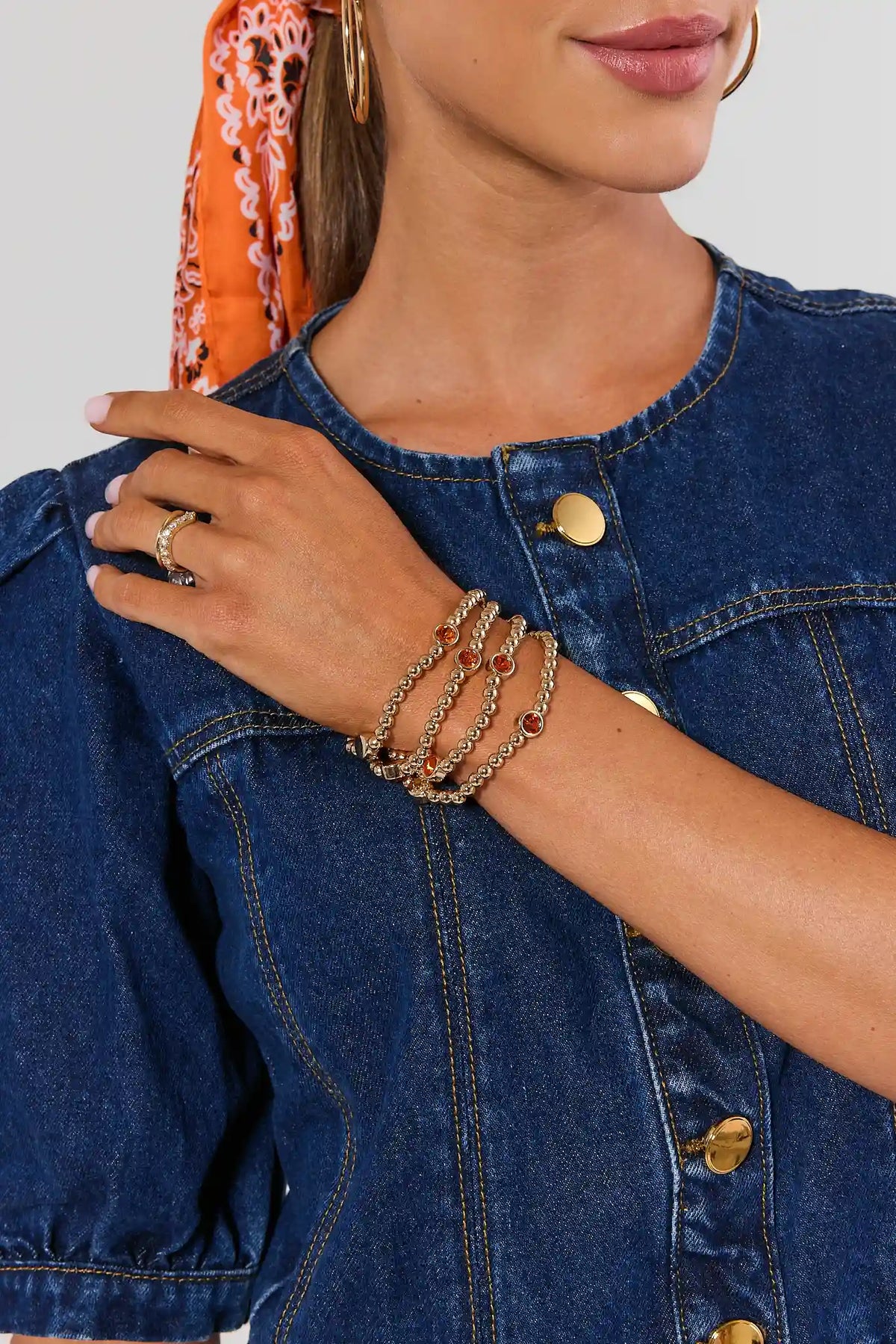 Gold and Orange Rhinestone Bracelet Set stacked on model's wrist, styled with denim | Avara