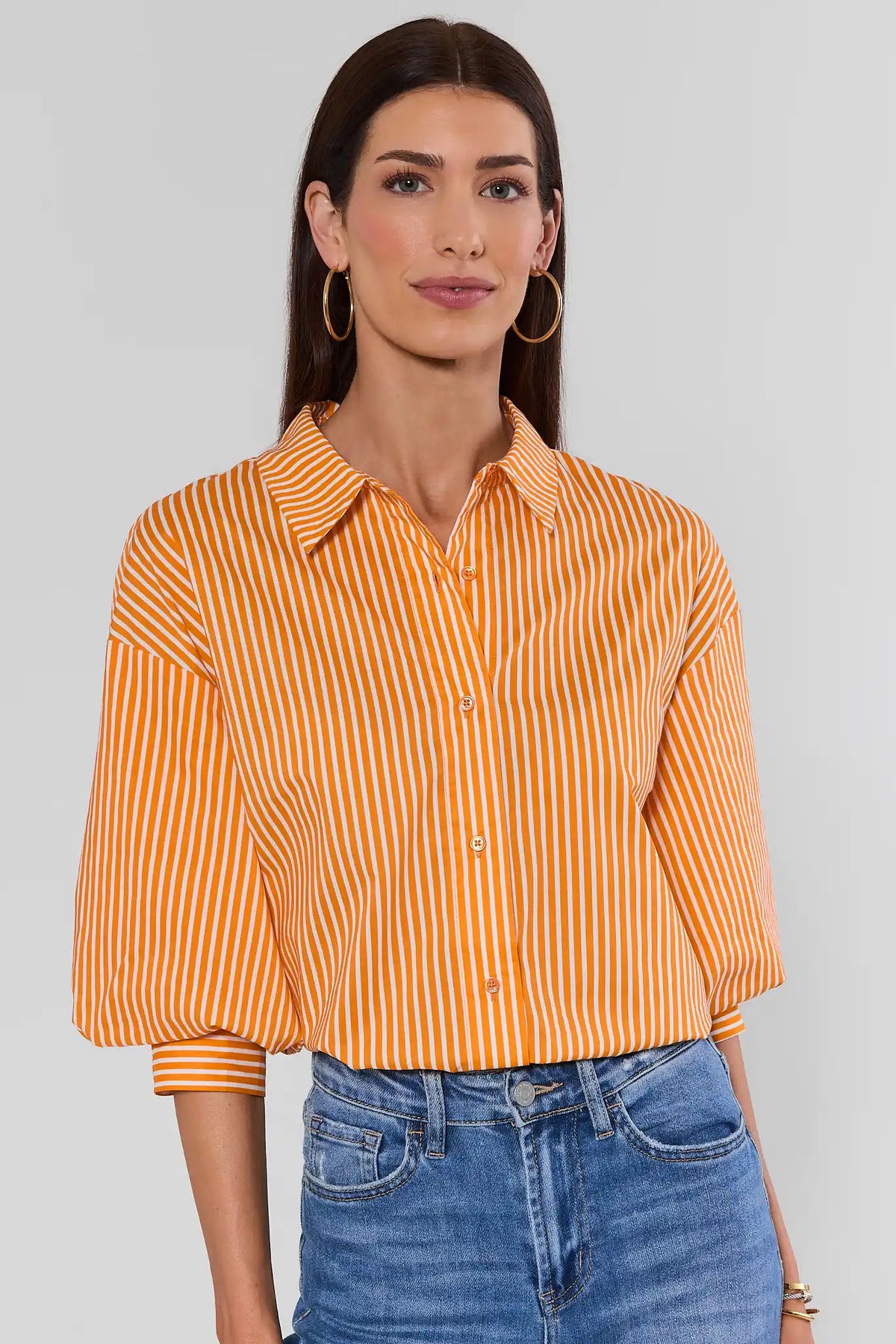 Orange striped button-up top with puff sleeves and spread collar, styled with blue jeans - Front View | Avara