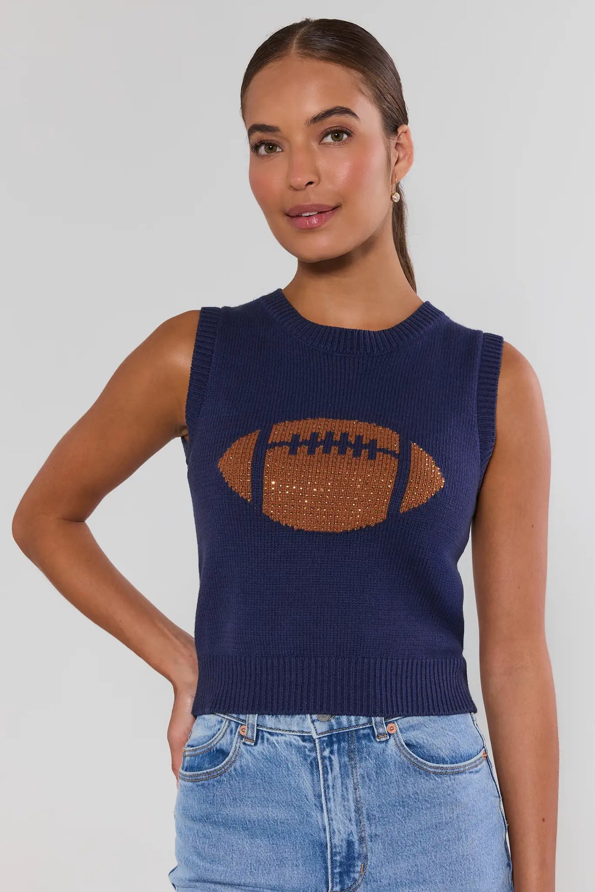 AJ Navy Football Sleeveless Knit Top with rhinestone football graphic, paired with light wash jeans - Front View On Model | Avara
