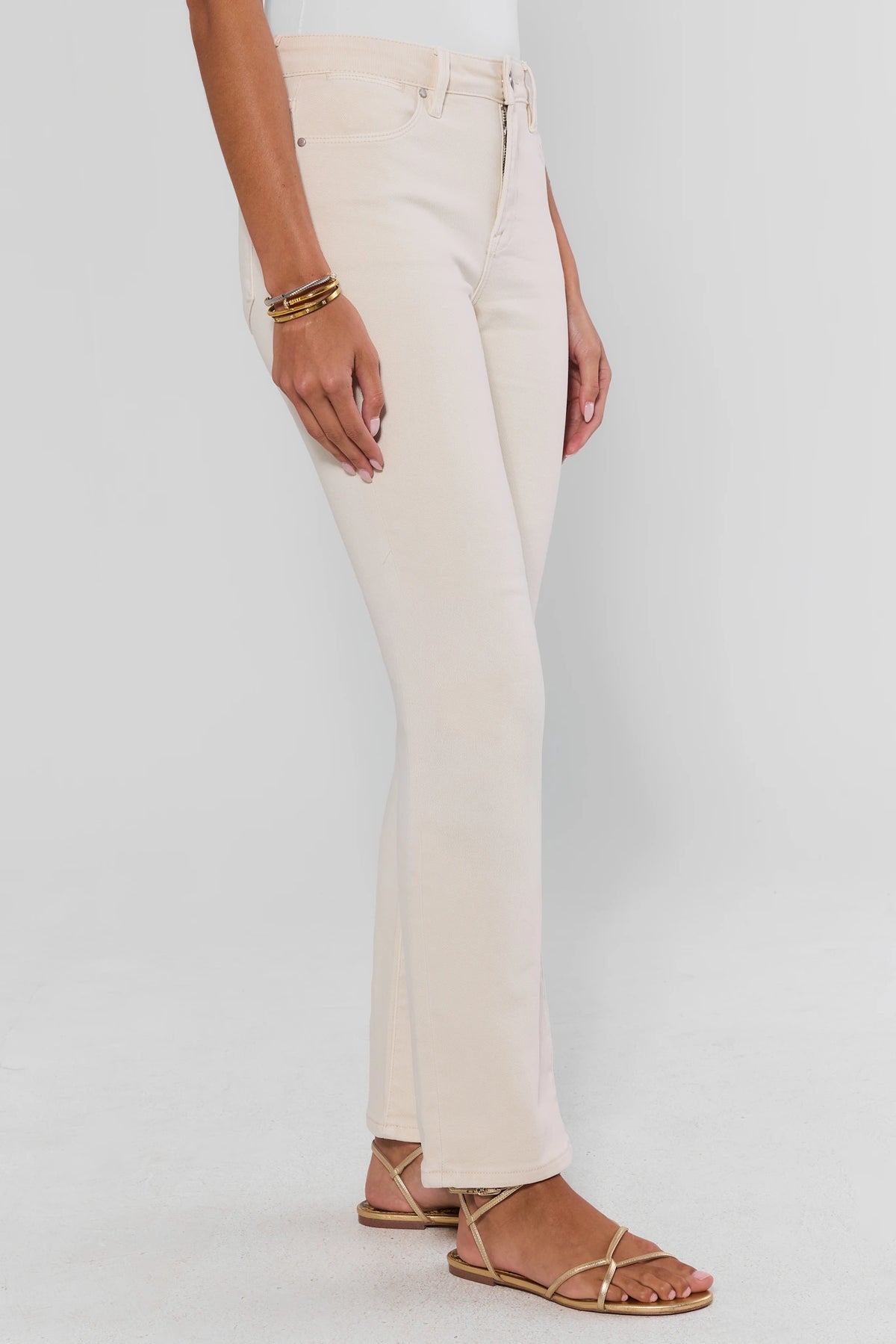Ecru straight leg jeans on model showing zip fly and straight silhouette with gold strappy sandals - Side View | Avara