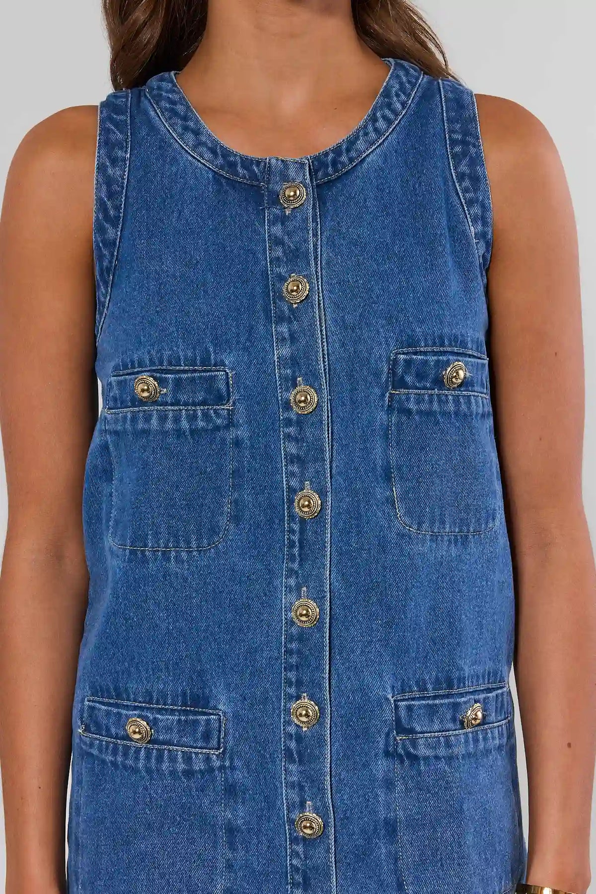Close-up of blue denim button-up dress showing ornate gold buttons and chest patch pockets - Detail View | Avara